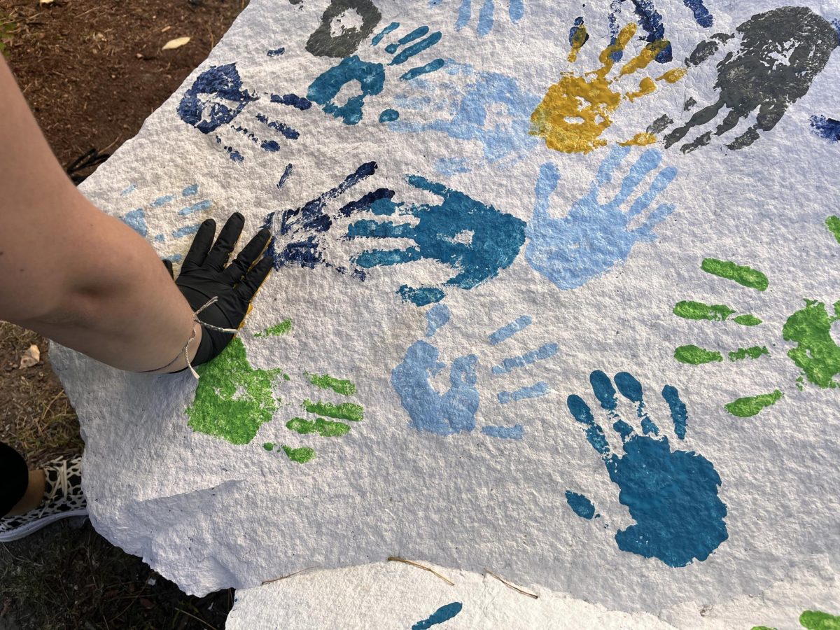 An new MCLA student adds their handprint to the rock outside Mark Hopkins Hall. 