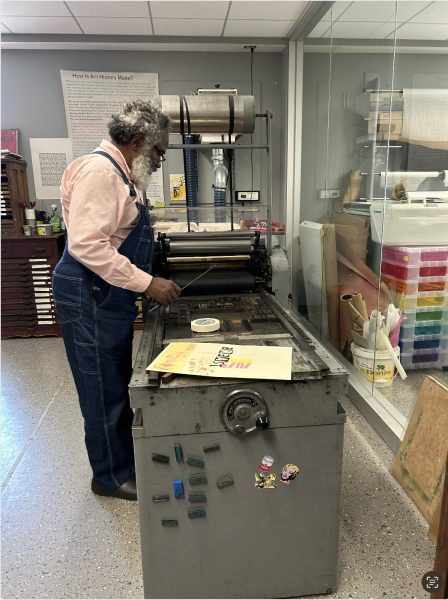 Amos Kennedy prepares the printing press for use during the Day of Dialogue at MCLA.